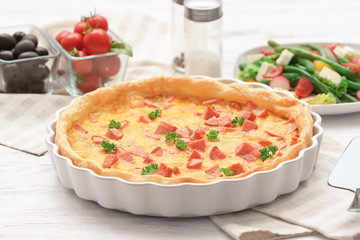 Delicious casserole with sausages in baking dish on table