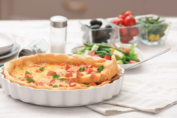 Delicious casserole with sausages in baking dish on table