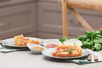 Plates with slices of delicious sausage casserole on table