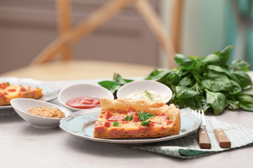 Plate with slice of delicious sausage casserole on table