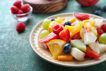 Plate with delicious fruit salad on table