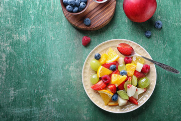 Plate with delicious fruit salad on table