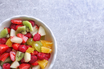 Bowl with delicious fruit salad on light background