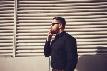 bearded man in sunglasses smoking a cigarette on a wooden background