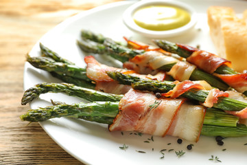 Plate with bacon wrapped asparagus on table, closeup