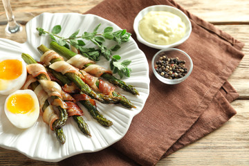 Plate with bacon wrapped asparagus on table