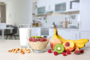 Composition with bowl of oatmeal, milk, berries and fruits on table indoors