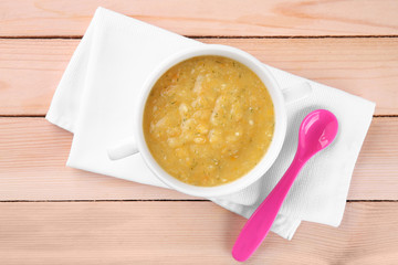 Bowl with creamy baby vegetable soup on wooden table