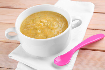 Bowl with creamy baby vegetable soup on wooden table