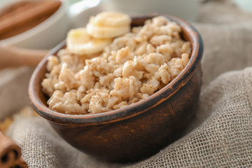 Tasty oatmeal with banana in bowl on table