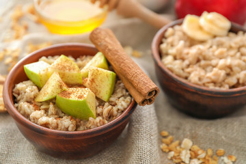 Tasty oatmeal with apple in bowl on table