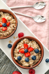 Tasty oatmeal with berries in bowls on table