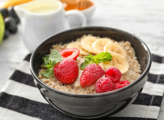 Tasty oatmeal with fruits in bowl on table