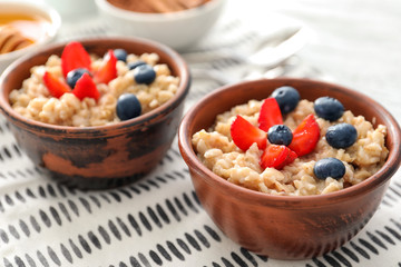 Tasty oatmeal with berries in bowls, close up