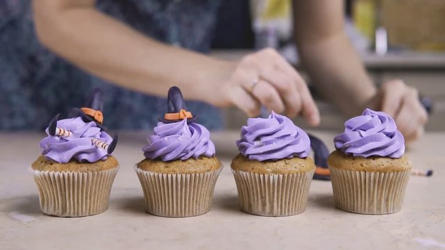 Decorating fun cup-cake with icing hat and legs. Muffin like witch. Halloween concept.