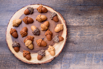 Healthy homemade Maple Acorn Cakelets, acorn shape cookies on wood slice serving board, server, tray. Wooden background. Top view.