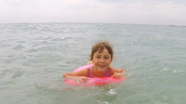 Happy child in an inflatable circle in the sea. A little girl in an inflatable circle is floating in the sea.