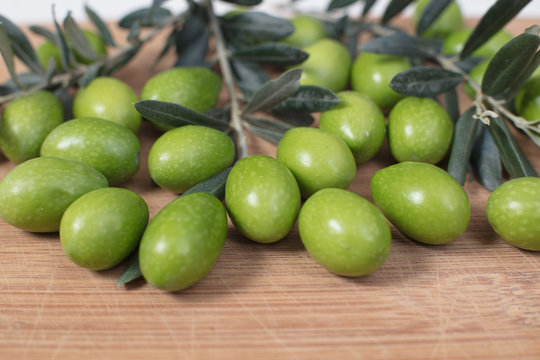 Harvested fresh olives with young olive twigs on wooden background