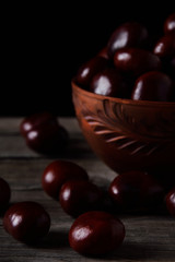  Fresh chestnuts in a bowl on an old wooden table. Group of chestnuts. Chestnuts - fruits horse chestnut - Aesculus hippocastanum. Dark background. Autumn background