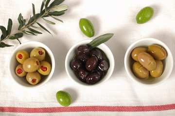 Three kind of olives and young olive branch on cloth napkin