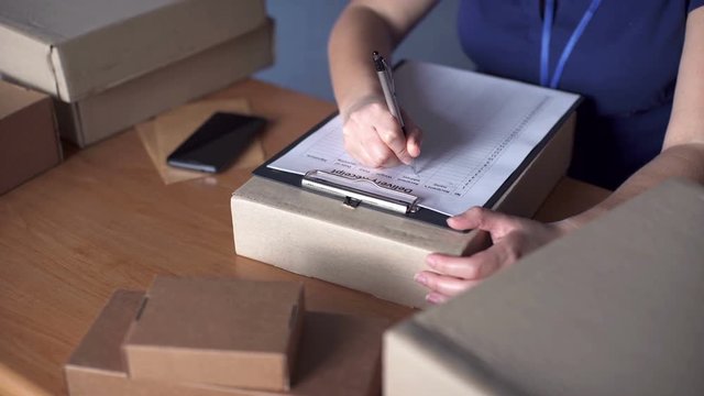 Courier writing on cardboard box at table