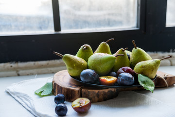 Studio shot plums and pears on plate heathy diet