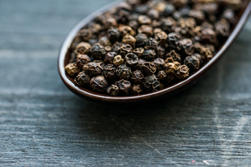 Close up black peppercorn in spoon dark background