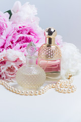 Peony essence in glass vials and fresh peony flowers on white leather background