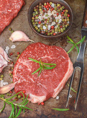 Fresh organic raw beef. Ingredients for making dinner - steaks, onion, garlic, rosemary, salt, pepper, olive oil. Selective focus