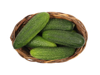 Small cucumbers in wooden wicker basket isolated on white background, top view
