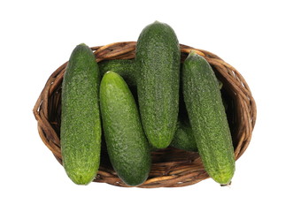 Small cucumbers in wooden wicker basket isolated on white background, top view