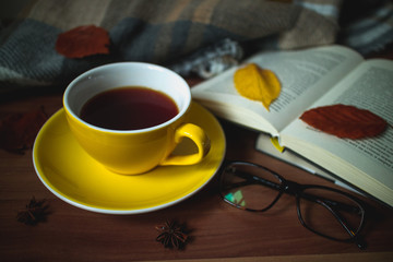 Yellow cup of tea with books and autumn leaves