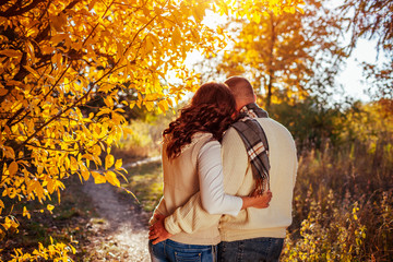 Middle-aged couple hugs in autumn forest among colorful trees