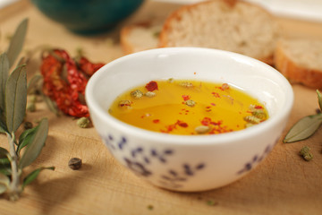 Close up view of  olive oil  in porcelain bowl with thyme and olive twig over wooden table  with a shallow depth of focus