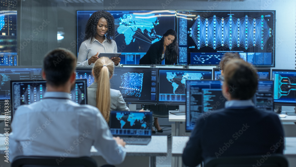 Poster Chief Project Engineer Consults Tablet Computer and Holds Briefing for a Team of Scientists that are Building Machine Learning System. Displays Show Working Model of Neural Network.