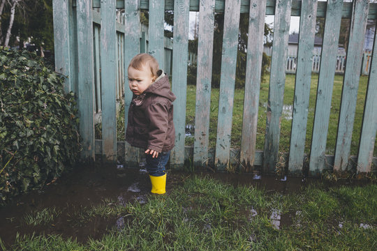 Cute young toddler boy in spring mud puddle - dirty