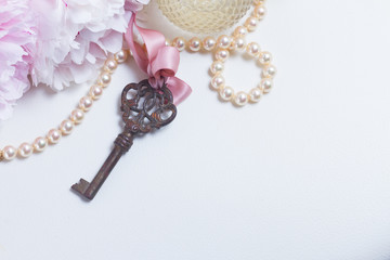 Skeleton key with peony flowers, glamour bottle and jewellery close up - love and wedding concept