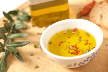 Close up view of  olive oil  in porcelain bowl with thyme and olive twig over wooden table  with a shallow depth of focus