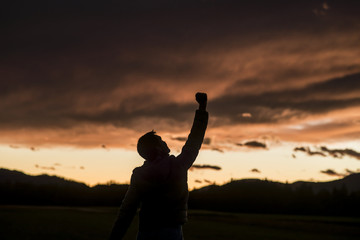 Fototapeta premium Jubilant man raising his fist against a sunset