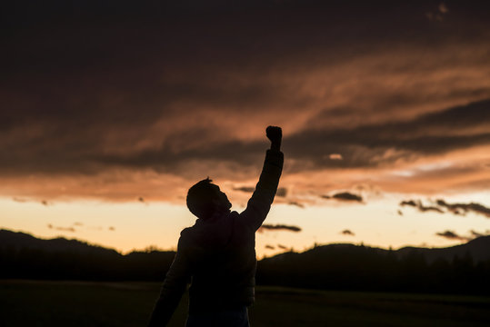 Jubilant man raising his fist against a sunset
