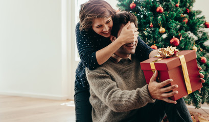 Young couple having fun celebrating Christmas with gifts.