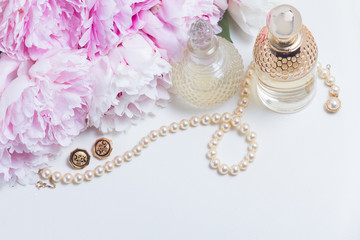 Female lifestyle scene with fresh pink peony flowers, glamour bottles and jewellery