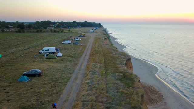 aerial footage of man riding a bicycle on beautiful coast line during sunset or sunrise