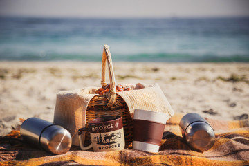 Picnic basket with bread, buns, rolls, thermoses and cups at the beach. Picnic outdoors