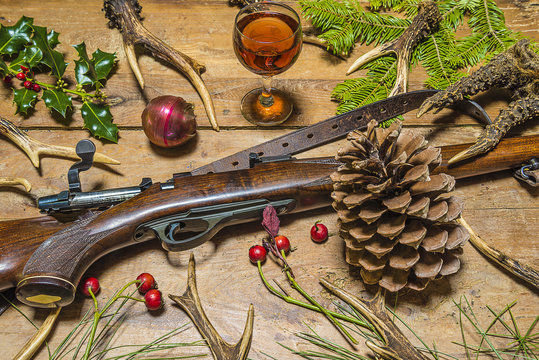 hunter's christmas/roe anters, glass of wine, hunting rifle and christmas decoration on rustic background