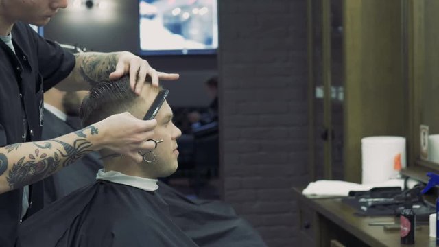 Barbershop. A creative hairdresser does a stylish haircut. A hairdresser creates a fashionable image for the young guy.