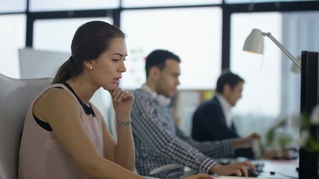  Business team working on computers in modern office, focus on young woman