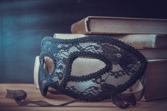 carnival mask and a stack of books