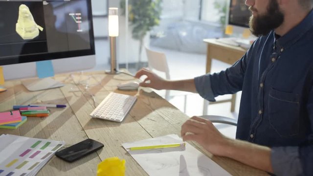 Designer working on a project, looking at concept model, sketching and working on computer.