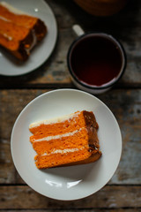 piece of orange cake on a white plate on a wooden table